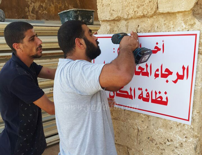 بالصور: لجنة إكرام الميت تُعلق يافطات ارشادية في مقبرة "طاسو" بمدينة يافا 