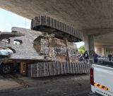 بالصور: جرافة ضخمة تسقط عن شاحنة وتتسبب بحادث قرب اللد 